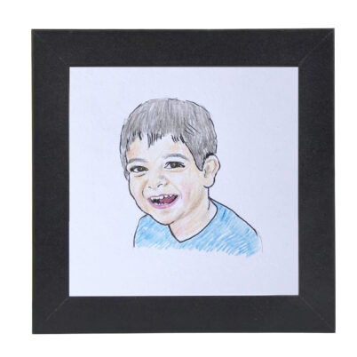 small framed child portrait drawing in black square frame with smiling boy with black hair, light brown skin, and a blue shirt.