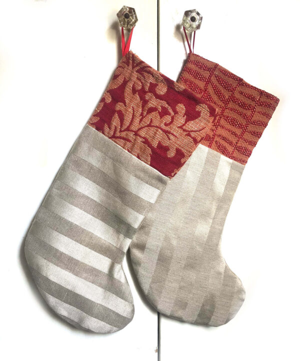 shiny silvery gold holiday stockings with red tops hang from knobs. handmade in California