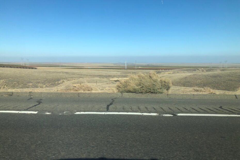 landscape photo from car window shows heavy grey layer of air pollution along the California Central Valley sky line
