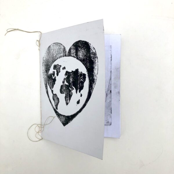 shows front of hand pressed handmade book. Cover has a globe within a heart.