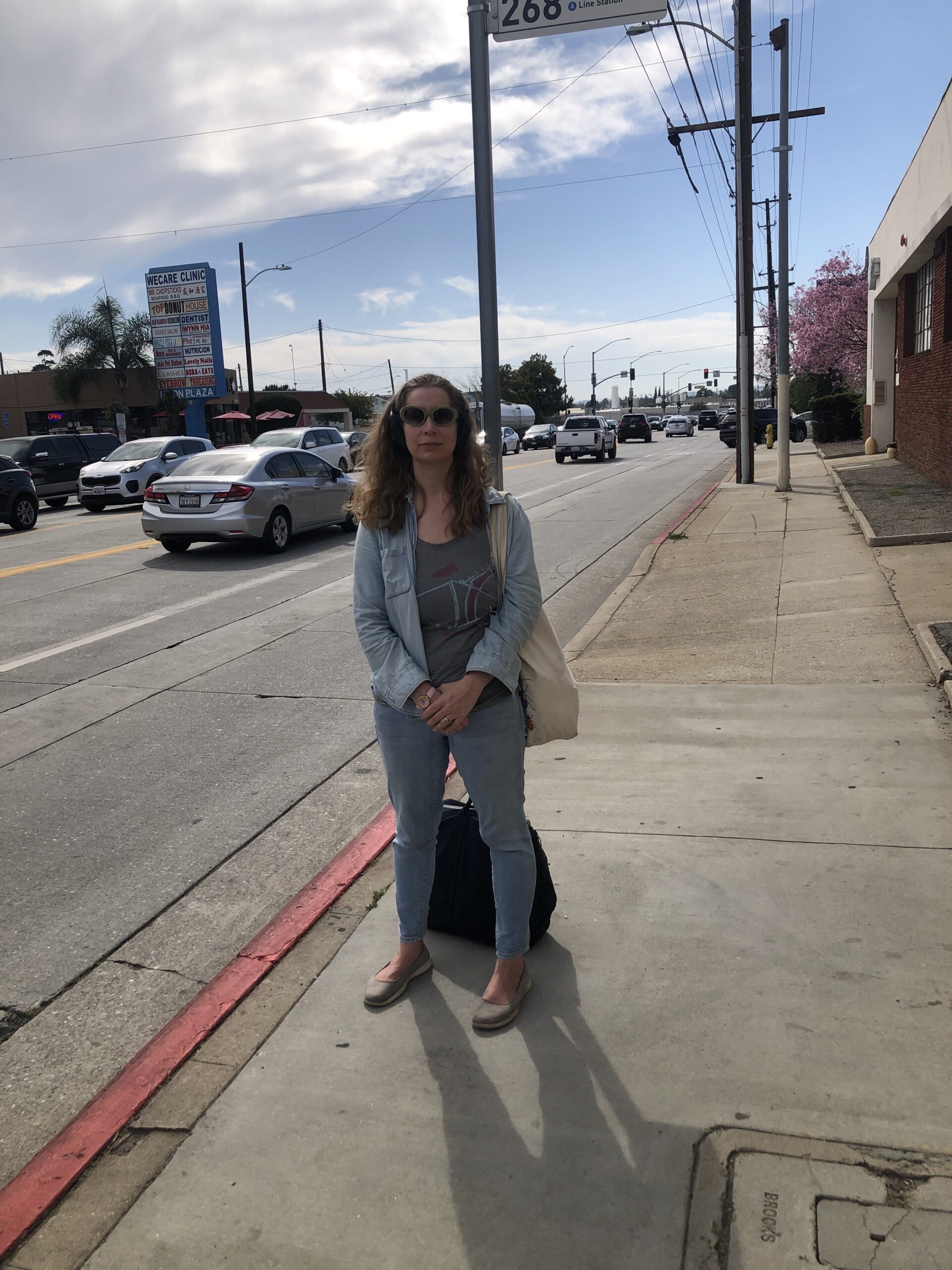 Photo shows Diana Kohne on the sidewalk next to a busy road with a lot of cars going by.