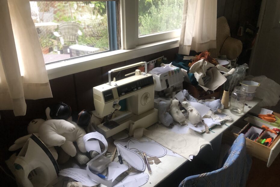 sewing machine on messy sewing table shows the process of making a sewing pattern. The purpose of the image is to illustrate why motivational cleaning tips don't work