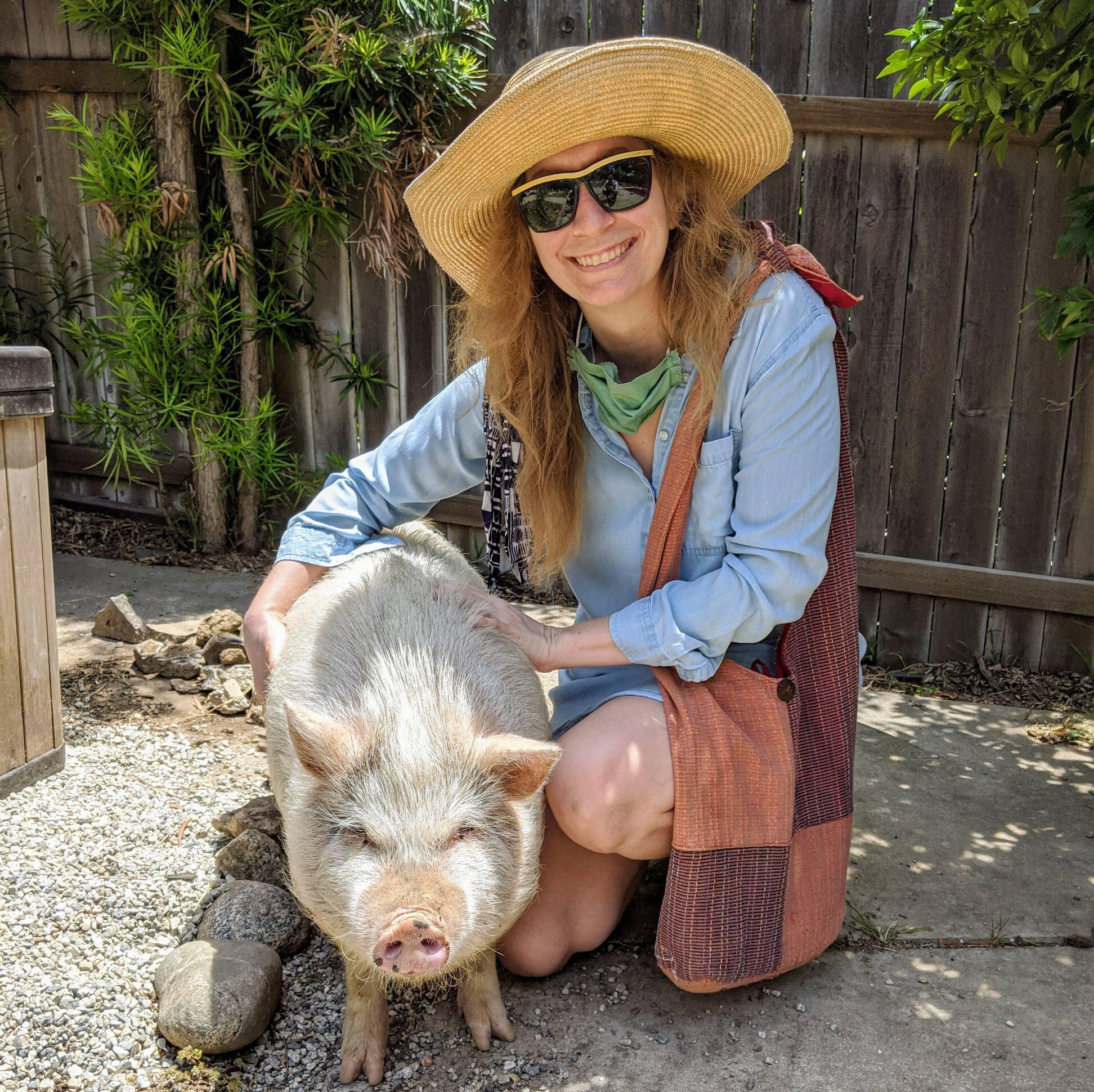 woman with hat posing with a pig, Diana, who operates this small project native plant landscaping business